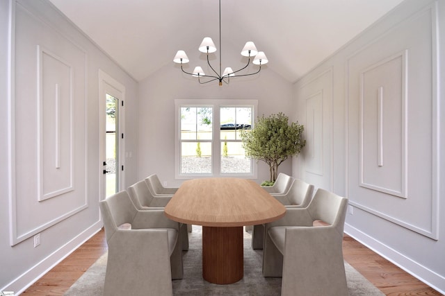 dining space with baseboards, vaulted ceiling, an inviting chandelier, and wood finished floors