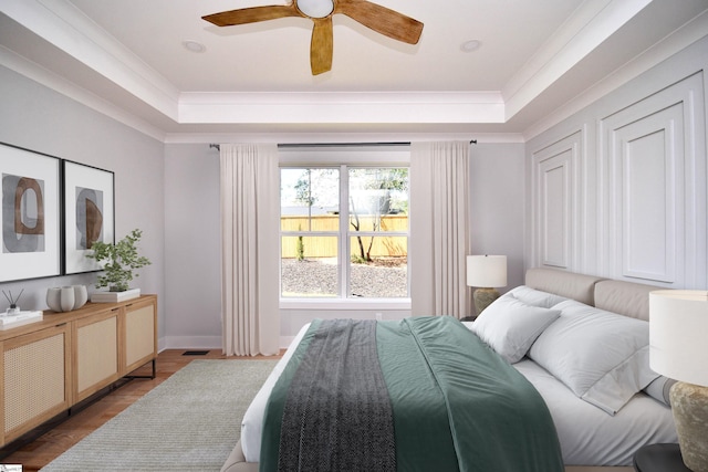 bedroom with a tray ceiling, baseboards, a ceiling fan, and visible vents