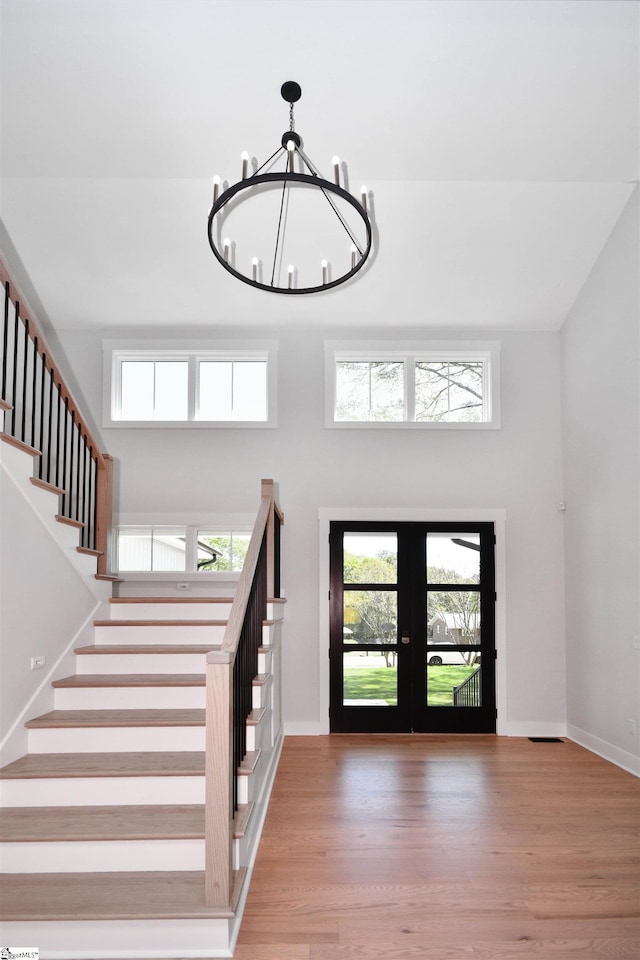 entrance foyer featuring a chandelier, a wealth of natural light, stairway, and french doors