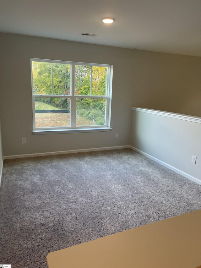 carpeted spare room featuring baseboards and visible vents