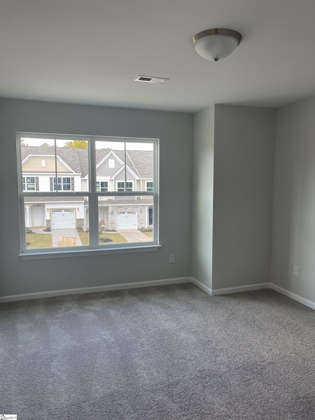 unfurnished room with carpet flooring, visible vents, and baseboards