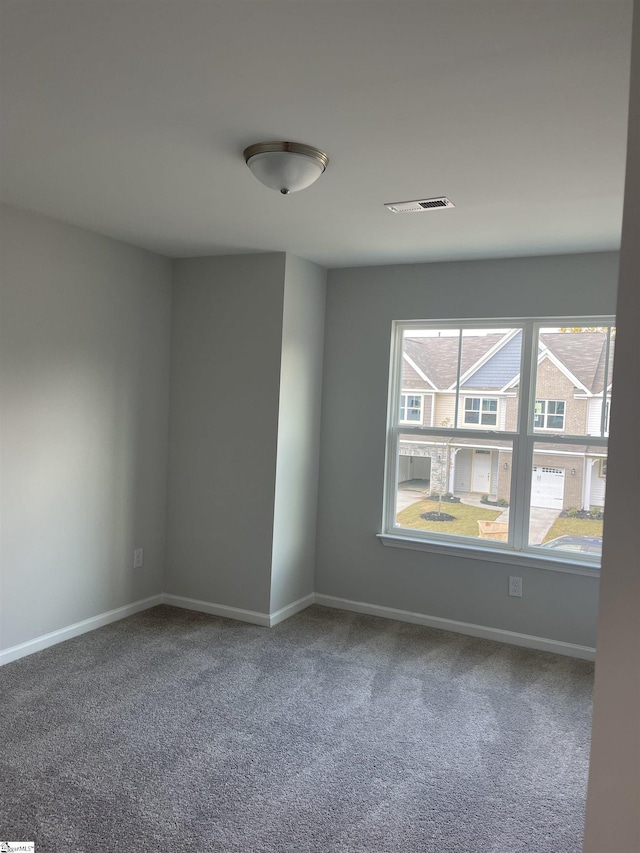 carpeted spare room featuring visible vents and baseboards