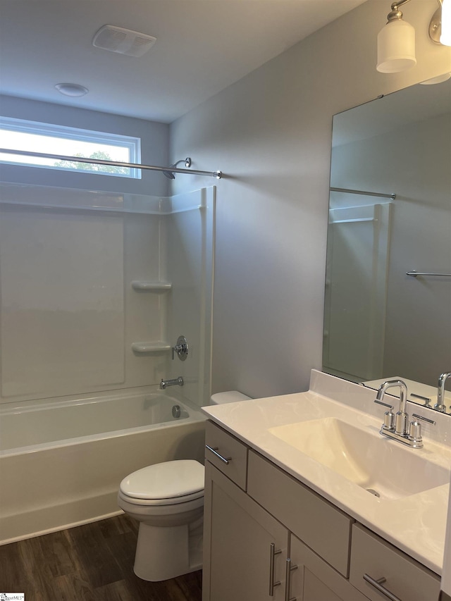full bathroom with visible vents, toilet, vanity, wood finished floors, and shower / bathtub combination