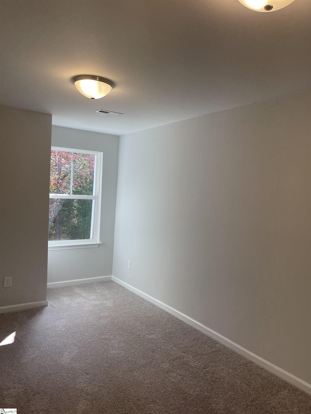 carpeted spare room with visible vents and baseboards