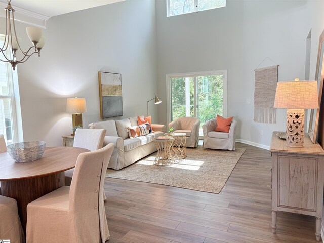 living area with a chandelier, a high ceiling, wood finished floors, and a wealth of natural light