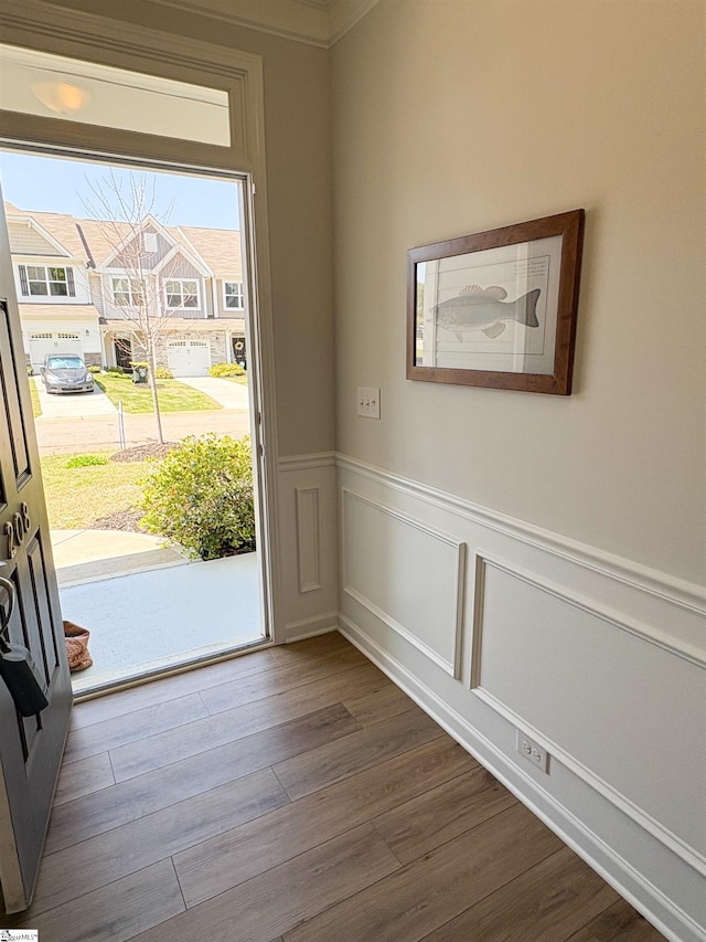 doorway to outside featuring a decorative wall, dark wood-style floors, and a wainscoted wall