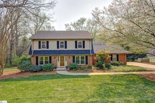 traditional-style home with a front yard, concrete driveway, brick siding, and roof with shingles