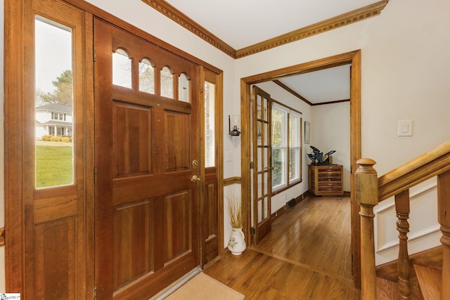 entrance foyer with ornamental molding, baseboards, stairway, and wood finished floors