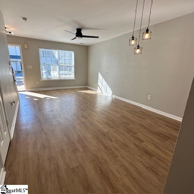 unfurnished living room with dark wood-style flooring, baseboards, and a ceiling fan
