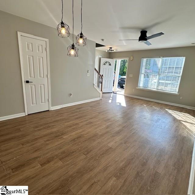 interior space featuring ceiling fan, baseboards, dark wood-style floors, and stairway