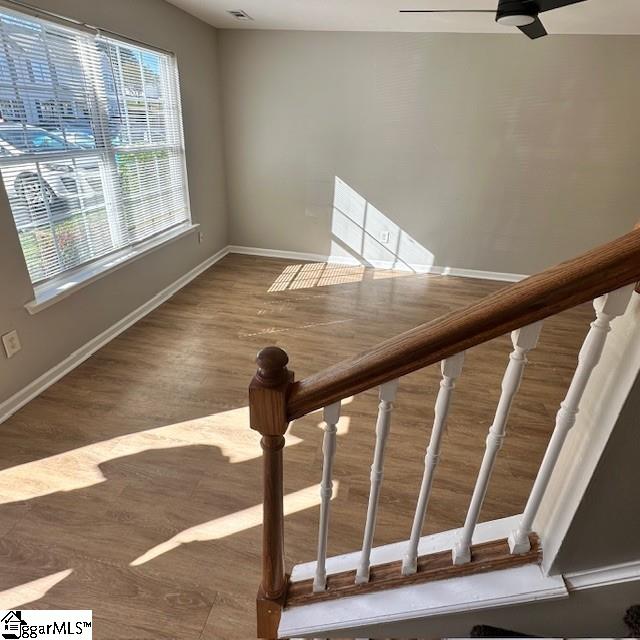 stairway featuring baseboards, a ceiling fan, and wood finished floors