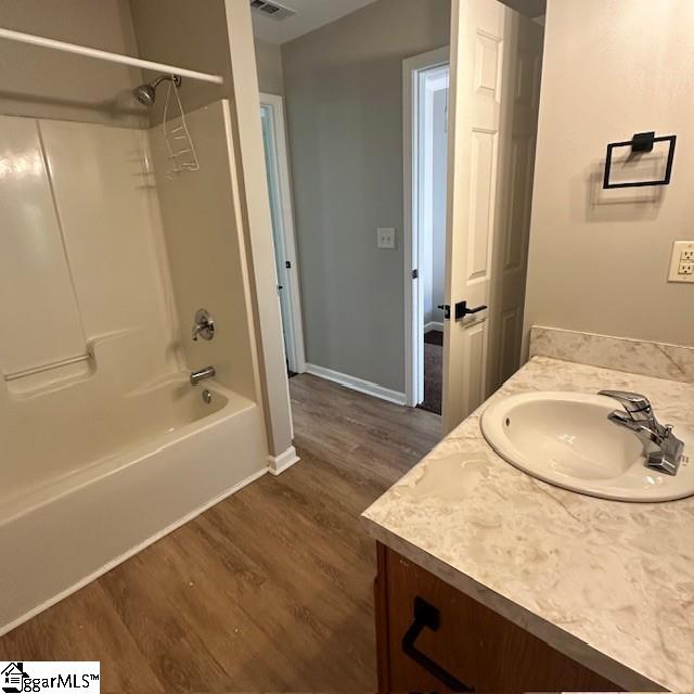 full bath with washtub / shower combination, vanity, baseboards, visible vents, and wood finished floors