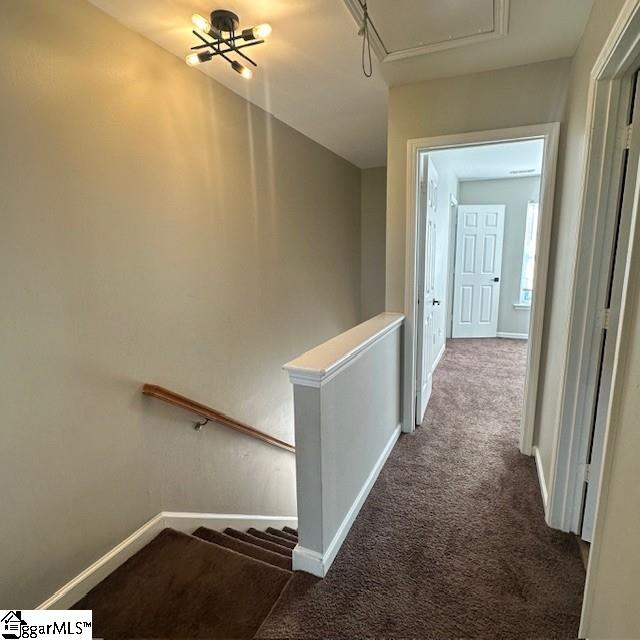corridor with an upstairs landing, baseboards, attic access, and carpet floors