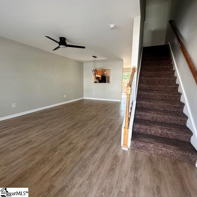staircase featuring wood finished floors, ceiling fan, and baseboards
