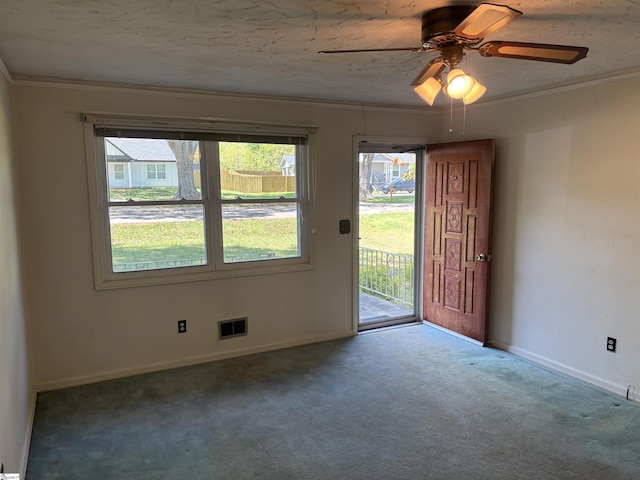 interior space with baseboards, crown molding, a ceiling fan, visible vents, and carpet