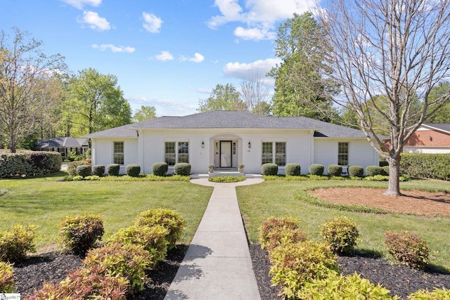 ranch-style home featuring roof with shingles, stucco siding, and a front lawn
