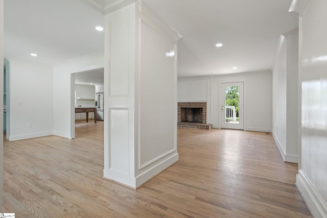 unfurnished living room featuring recessed lighting, light wood-style flooring, and a brick fireplace