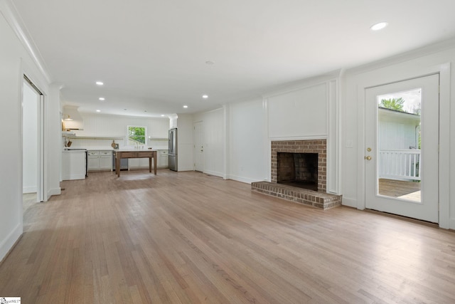 unfurnished living room with light wood finished floors, a fireplace, ornamental molding, and recessed lighting