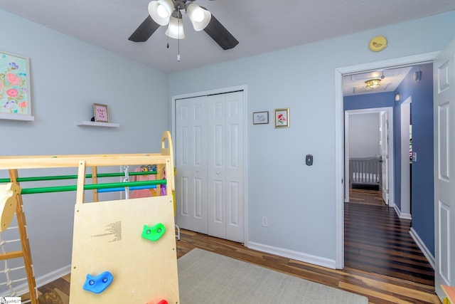 bedroom featuring a closet, baseboards, a ceiling fan, and wood finished floors