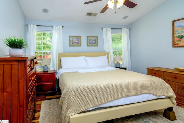 bedroom featuring visible vents, multiple windows, wood finished floors, and a ceiling fan