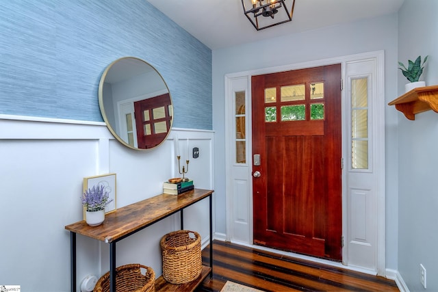 entryway with a notable chandelier, wainscoting, and dark wood finished floors