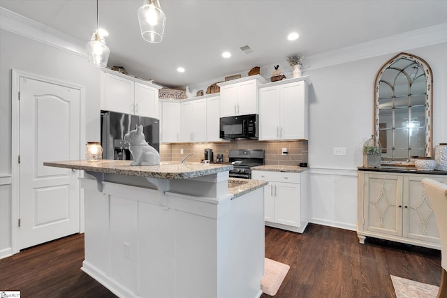 kitchen featuring crown molding, a kitchen breakfast bar, black microwave, stainless steel fridge, and gas range oven