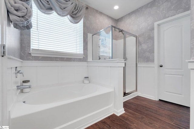 bathroom with wainscoting, wallpapered walls, a stall shower, and wood finished floors