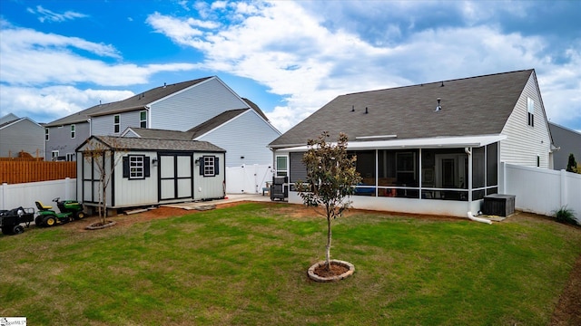 rear view of house featuring a shed, a sunroom, a fenced backyard, an outdoor structure, and a lawn