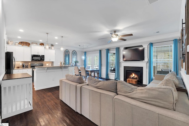 living room featuring ornamental molding, ceiling fan, dark wood-style floors, and a wealth of natural light