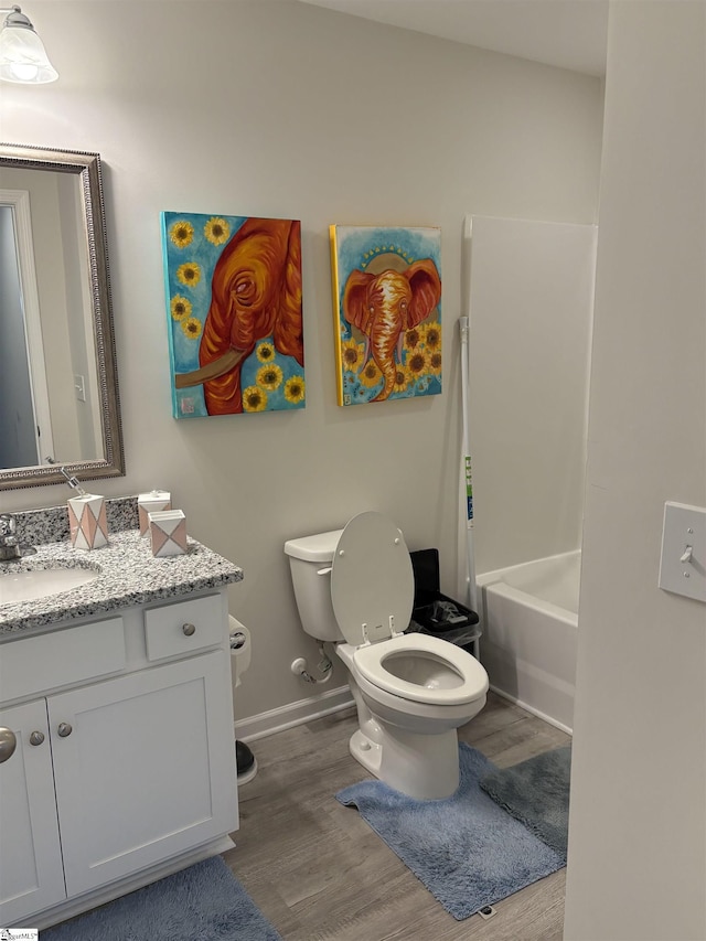 bathroom featuring wood finished floors, toilet, vanity, shower / tub combo with curtain, and baseboards