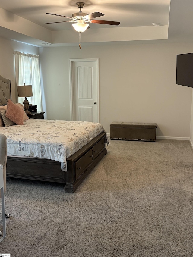 carpeted bedroom featuring ceiling fan, baseboards, and a raised ceiling