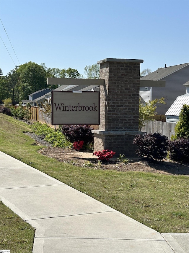 community / neighborhood sign featuring a lawn and fence