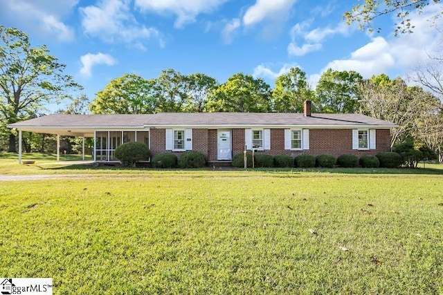 ranch-style house featuring a carport, a chimney, a front yard, and brick siding