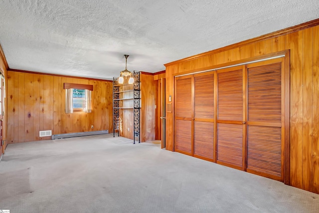 unfurnished living room featuring baseboard heating, a textured ceiling, wooden walls, and visible vents