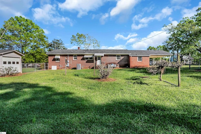 rear view of house featuring brick siding, fence, a gate, and a lawn
