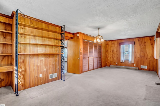 interior space featuring visible vents, a baseboard radiator, wood walls, and a textured ceiling