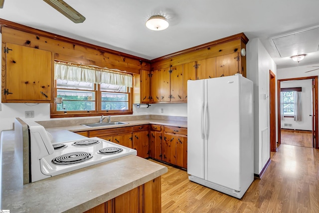 kitchen featuring a sink, light countertops, brown cabinetry, and white appliances