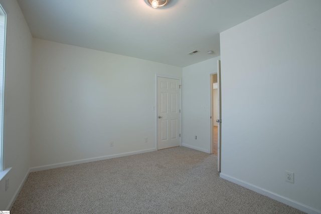 empty room with visible vents, light colored carpet, and baseboards