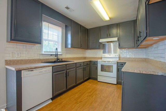 kitchen with a sink, light countertops, white appliances, under cabinet range hood, and light wood finished floors