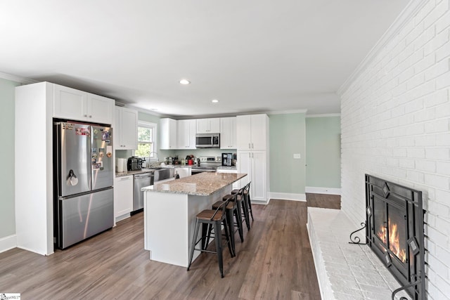 kitchen with crown molding, a kitchen bar, white cabinets, a kitchen island, and appliances with stainless steel finishes