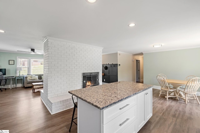 kitchen with crown molding, white cabinets, light stone countertops, and a fireplace