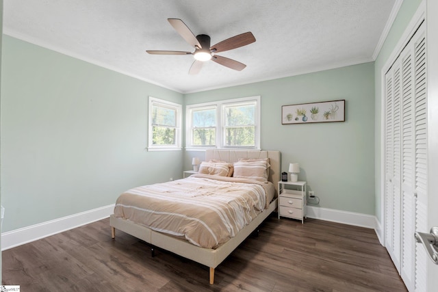 bedroom featuring a closet, baseboards, dark wood-style flooring, ornamental molding, and a ceiling fan