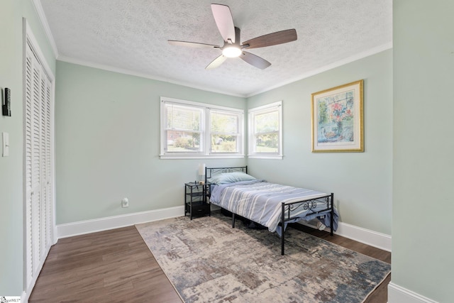bedroom with crown molding, a textured ceiling, a ceiling fan, wood finished floors, and baseboards