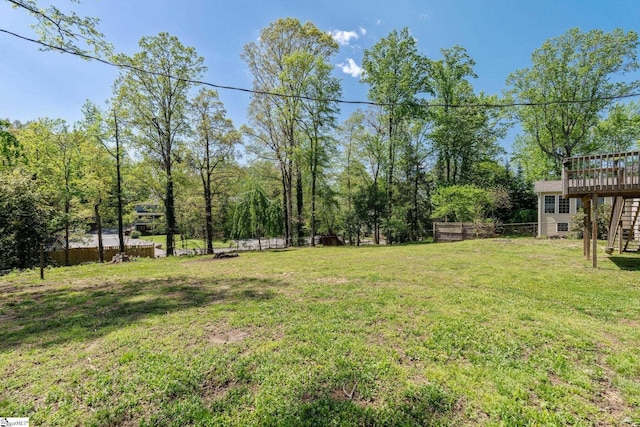 view of yard with stairway, a deck, and fence