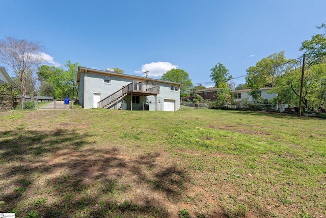 view of yard featuring a garage, stairs, a deck, and fence