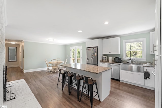 kitchen with a wealth of natural light, a kitchen breakfast bar, crown molding, and appliances with stainless steel finishes