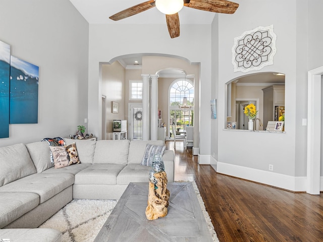 living area with baseboards, arched walkways, ornamental molding, ceiling fan, and wood finished floors
