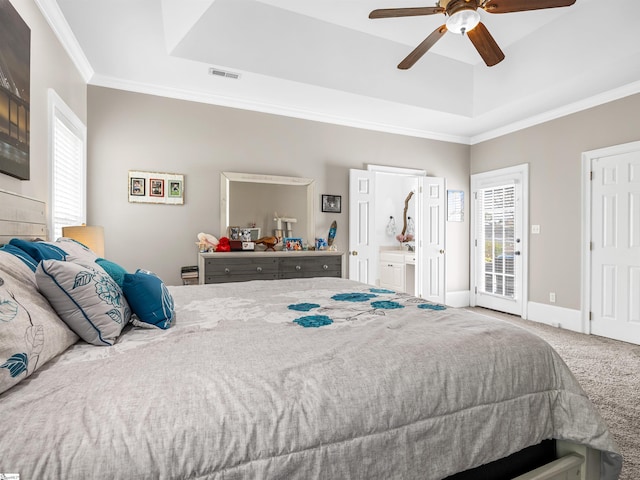 carpeted bedroom with access to outside, baseboards, ornamental molding, visible vents, and a tray ceiling