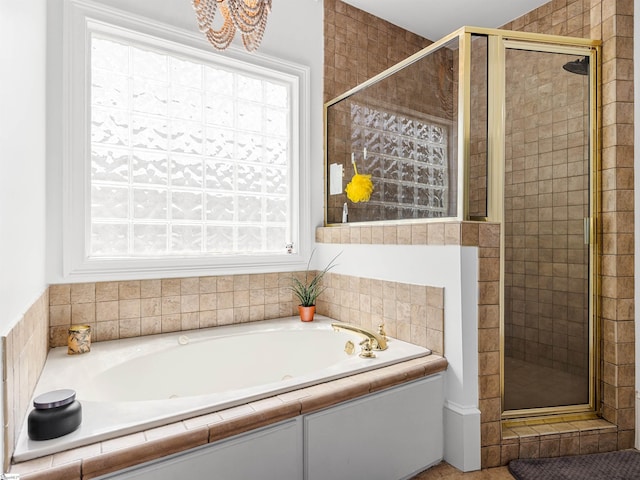 bathroom with a shower stall, a bath, and an inviting chandelier