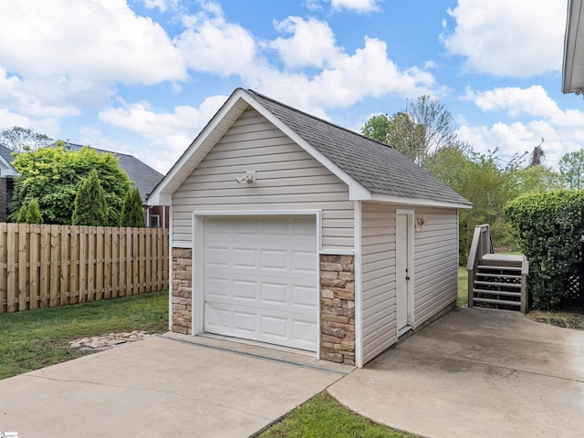 detached garage featuring fence and driveway